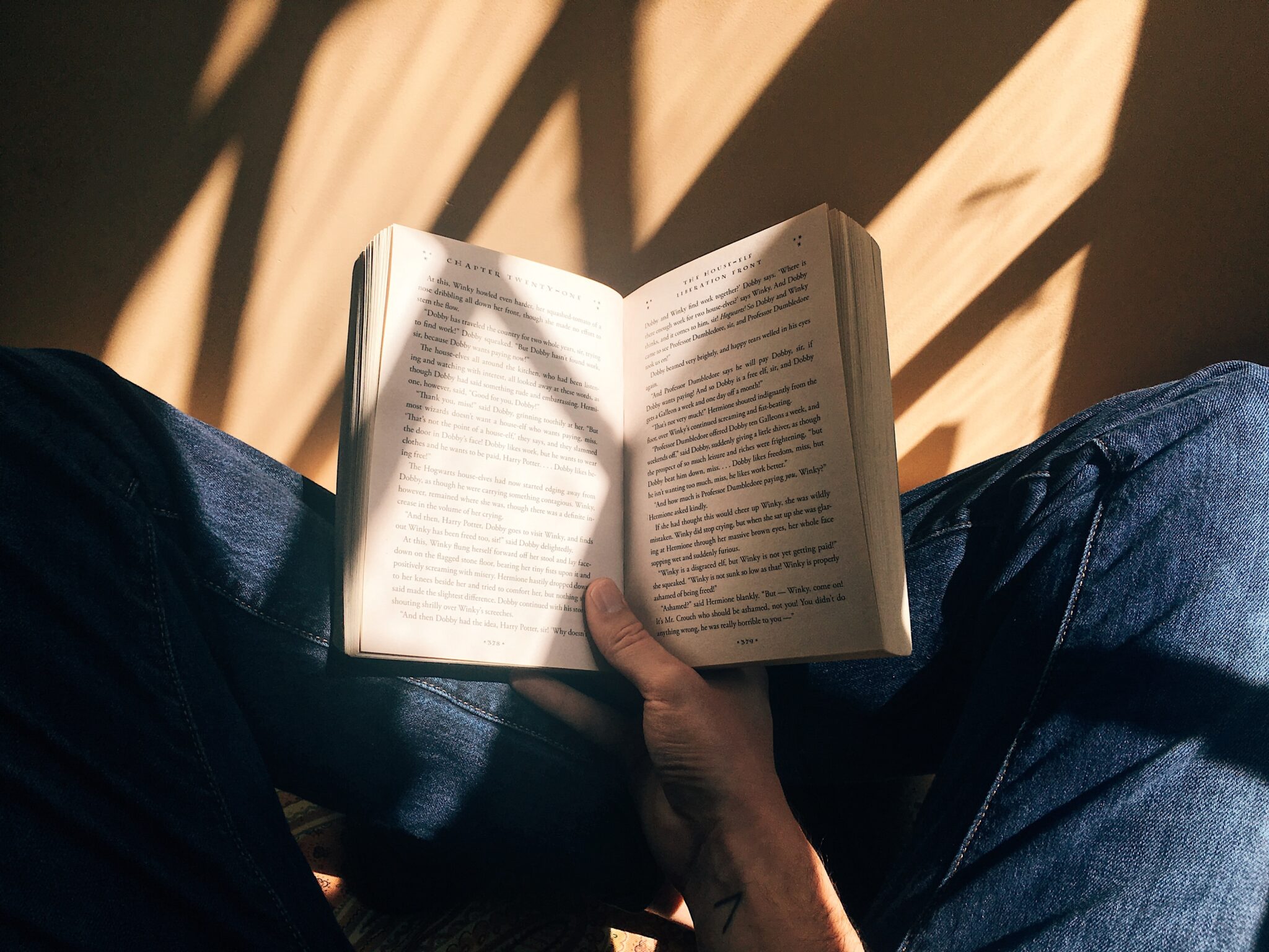 Bilde av person som leser bok, sett fra den som leser.