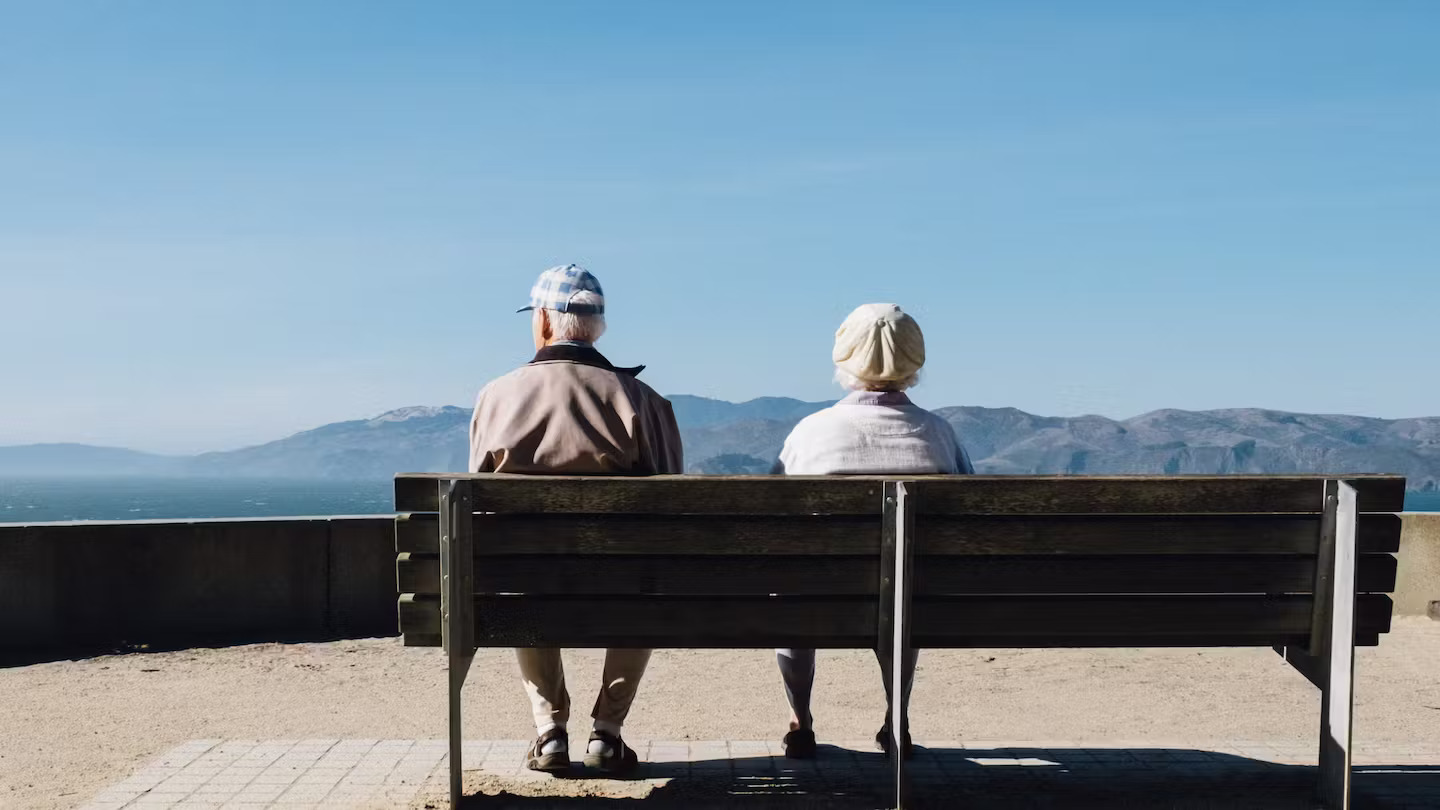 Bilde av to eldre mennesker på en parkbenk.